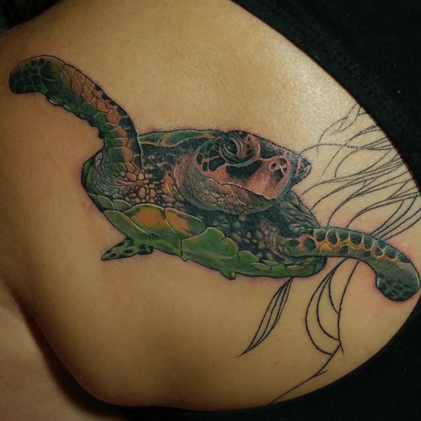Sea turtle tattoo with a green shell and floral linework
